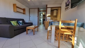 Een woonkamer met een bank, een salontafel en een eethoek met een tafel en stoelen.