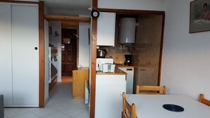 Eine kompakte Küche mit Essbereich, ausgestattet mit Kühlschrank, Mikrowelle, Kaffeemaschine und einer kleinen Kochinsel.