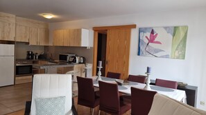 Una cocina moderna con armarios de madera, un comedor con mesa y sillas, y un cuadro en la pared.