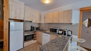 A compact kitchen with wooden cabinets, a built-in oven, a microwave, a toaster, and a coffee maker.