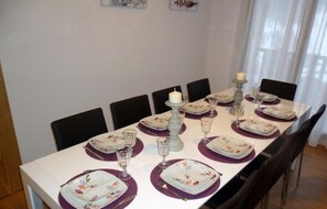 A dining table set with plates, glasses, and cutlery, surrounded by chairs. - JULIA 2/5-103 m²- 2 hab- 7 pers. balco- EL TARTER -06691 (SANT PERE DEL TARTER)