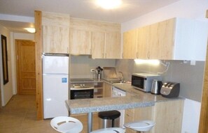 A compact kitchen with wooden cabinets, a built-in microwave, a toaster, and a stainless steel refrigerator. - JULIA 2/5-103 m²- 2 hab- 7 pers. balco- EL TARTER -06691 (SANT PERE DEL TARTER)