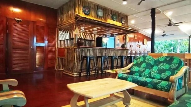 Eine Bar mit Holzausstattung, eine Sitzecke mit gepolstertem Sofa und Deckenventilatoren.