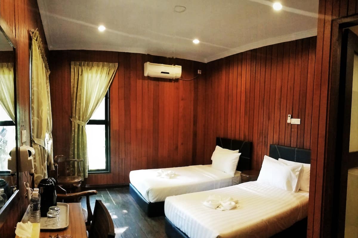 Une chambre d’hôtel avec deux lits, des panneaux de bois au mur, un bureau avec un plateau, un miroir et un appareil de climatisation.