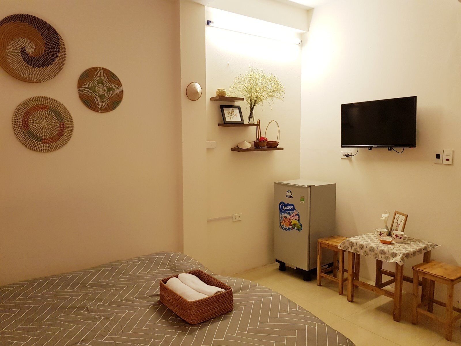 A small, cozy room with a bed, a refrigerator, a television, and a small table with chairs.