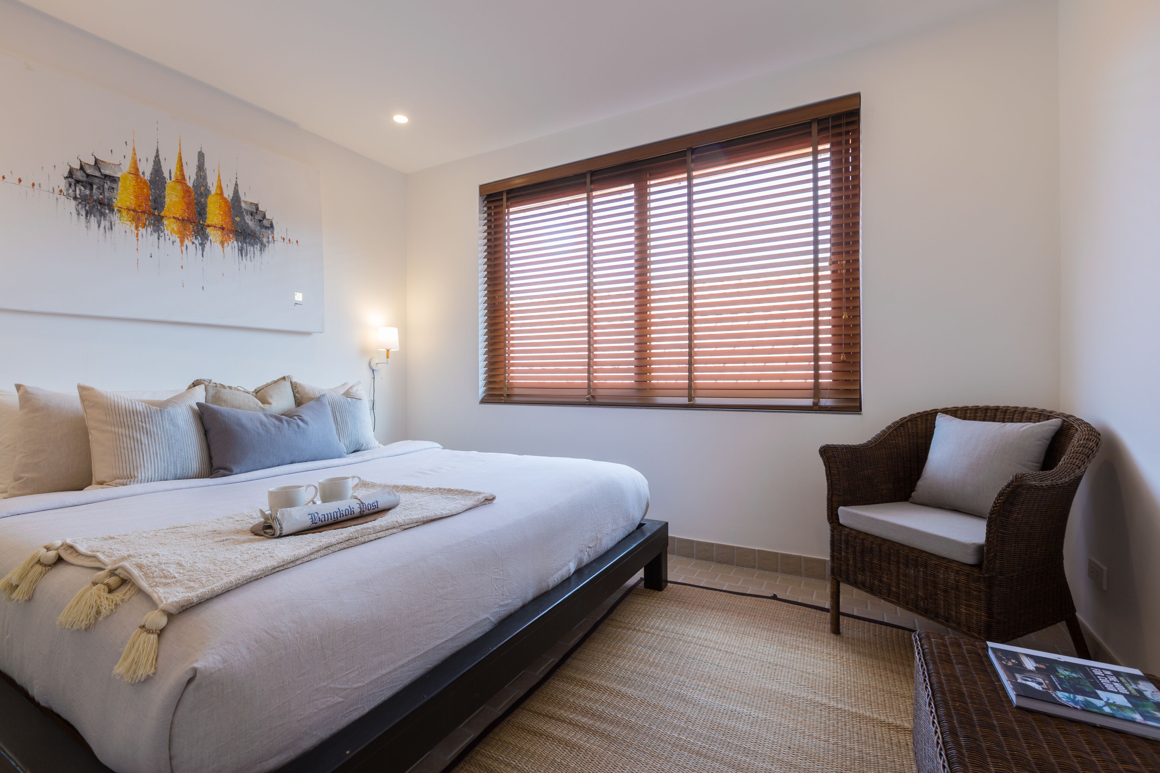 Un dormitorio con una cama grande, una silla, un ventanal con persianas y una obra de arte en la pared.