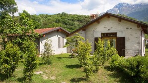 Edifici rústic amb una porta de fusta i un petit jardí a la façana.