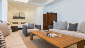 A modern living room with a sofa, two armchairs, a wooden coffee table, and a cabinet. - Papaya Studio (Koh Samui)