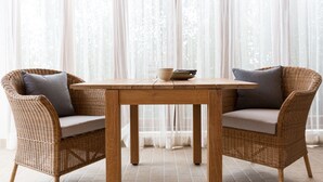 A wicker dining set with a table and two chairs, a bowl, and a book on the table. - Papaya Studio (Koh Samui)