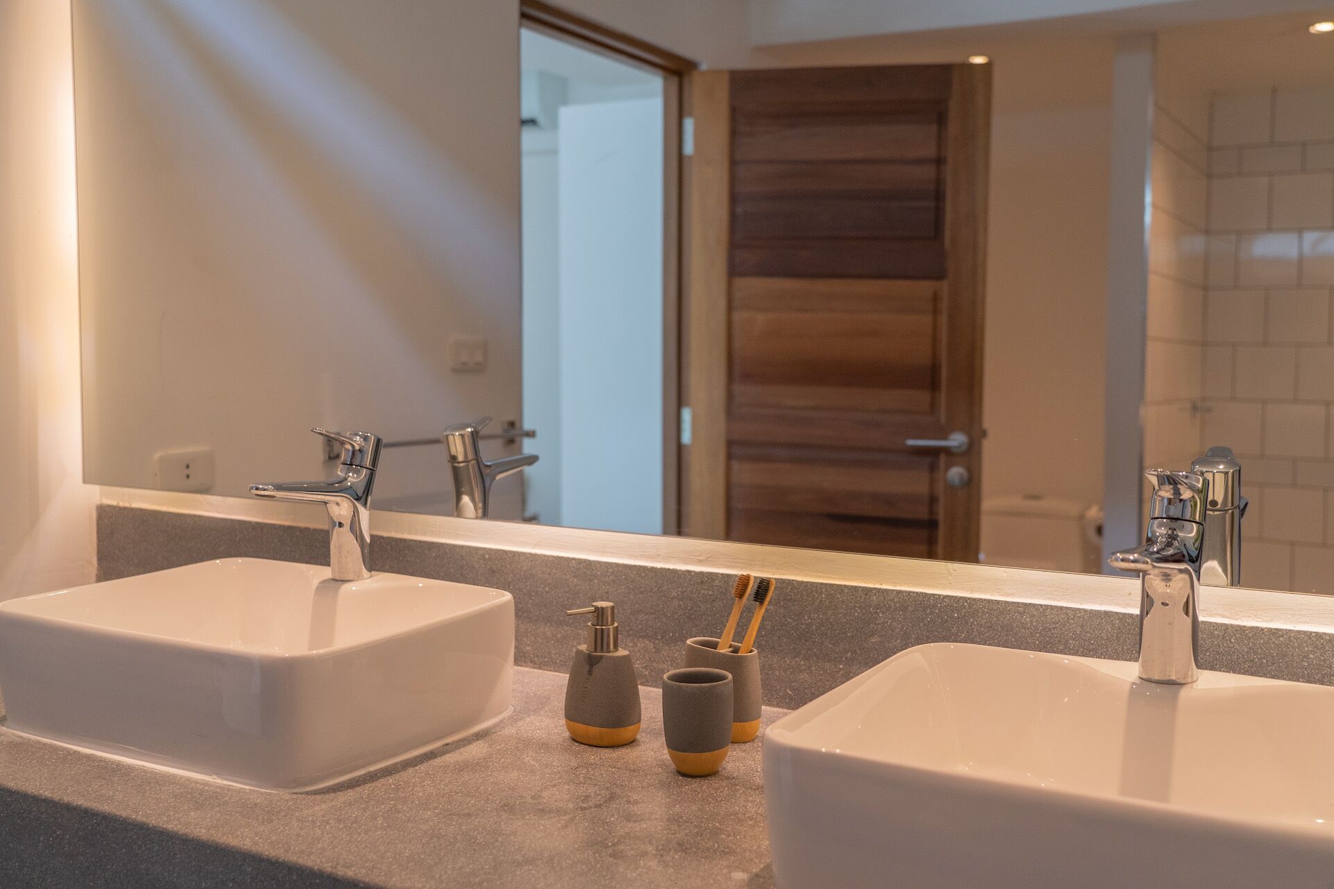 A bathroom with two sinks, a mirror, and a door in the background.