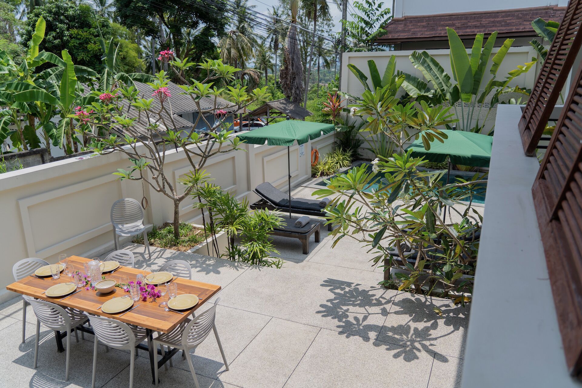 A patio with a dining table set for four, surrounded by chairs, and a small pool area with lounge chairs.