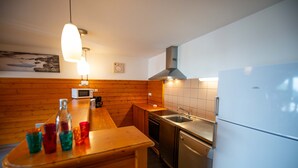 Et moderne køkken med træpaneler, en stålvask, en mikrobølgeovn og et køleskab.