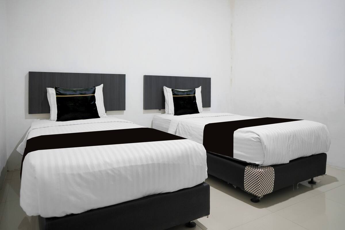 Two beds with black and white bedding, grey headboards, and a checkered throw on one bed.