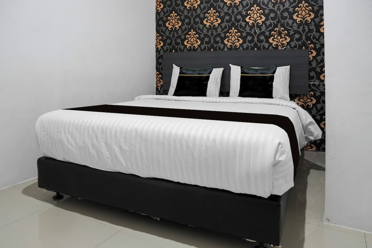 A neatly made bed with a black frame and white bedding, a dark headboard, and patterned wallpaper.