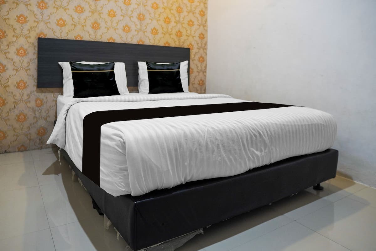 A neatly made bed with a dark headboard, white bedding, and a patterned wallpaper background.