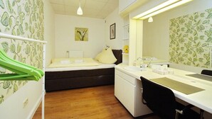 A small, cozy room with a bed, a desk with a mirror, and a sink. - FeWo Borkum in Papenburg (Papenburg)