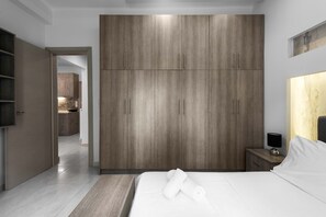 Un dormitorio moderno con un armario grande, una mesita de noche con lámpara y una cama bien hecha.