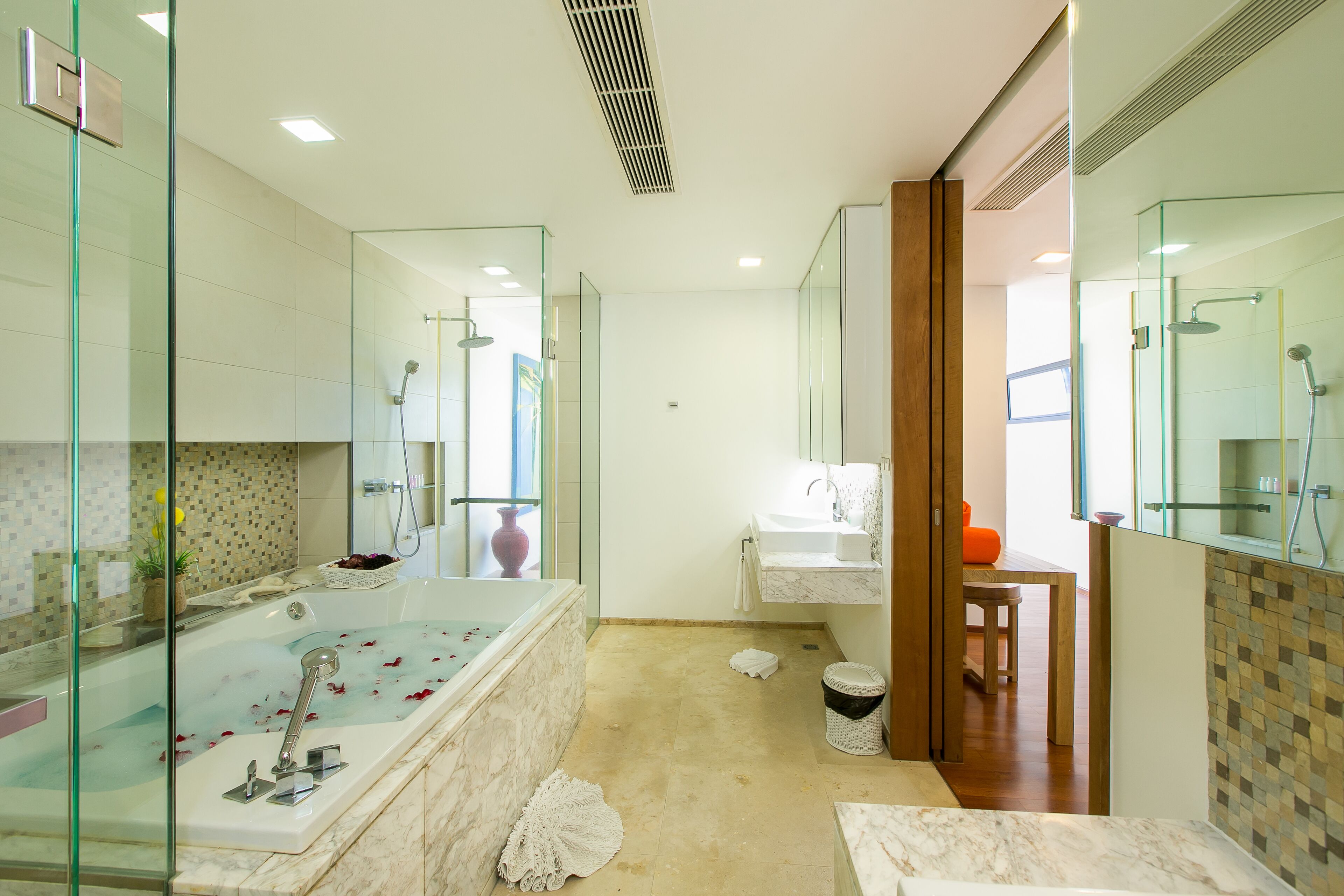 A modern bathroom with a glass-enclosed shower, a marble bathtub, and a sink with a mirror above it.