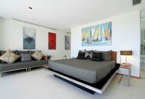 Een moderne slaapkamer met een bed, een bank en kunstwerken aan de wanden.