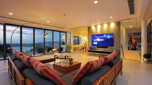 Een moderne woonkamer met een grote televisie, comfortabele zitplaatsen en uitzicht op de omgeving.