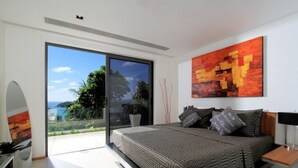 Een moderne slaapkamer met een groot bed, uitzicht door een schuifdeur en een schilderij aan de muur.
