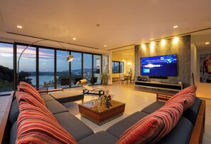 Een moderne woonkamer met een grote televisie, comfortabele zithoek en uitzicht op de omgeving.
