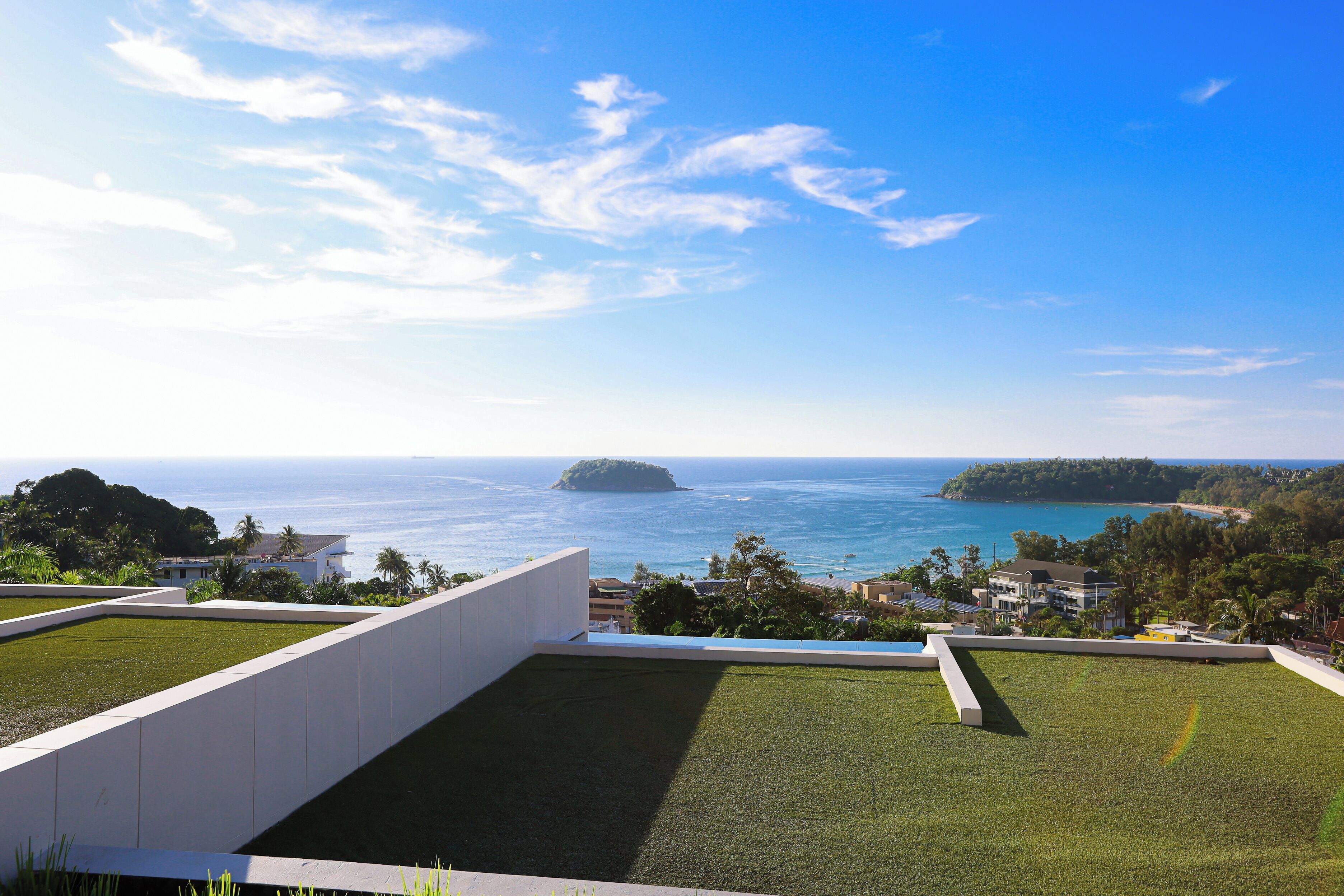 A rooftop terrace with a view of the ocean and a distant island.