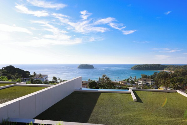 A rooftop terrace with a view of the ocean and a distant island.