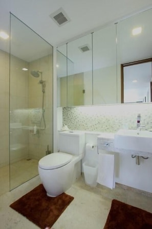 A modern bathroom with a glass-enclosed shower, a white toilet, a sink, and a mirror above the vanity. - Luxury Ocean View Apartment Kata B22 near Kata Beach (Karon)