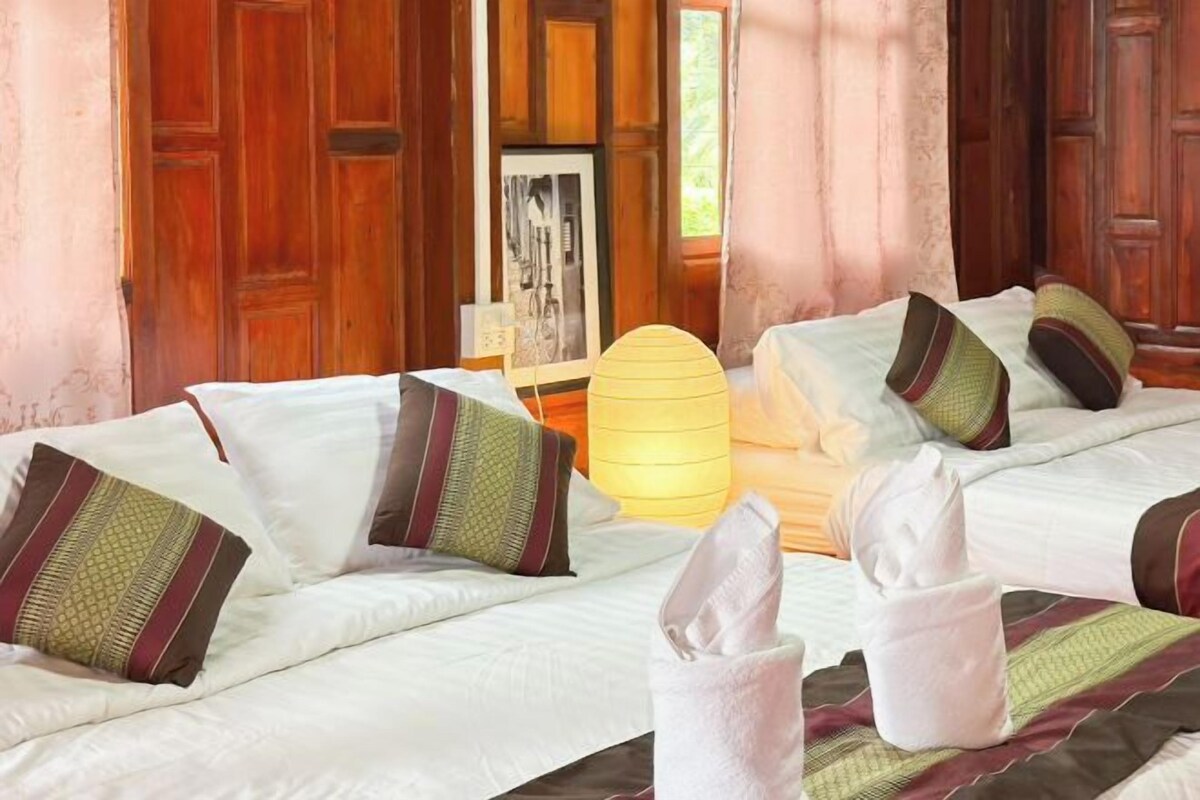 Habitación de hotel con dos camas, puertas de madera, un cuadro en la pared y una lámpara.