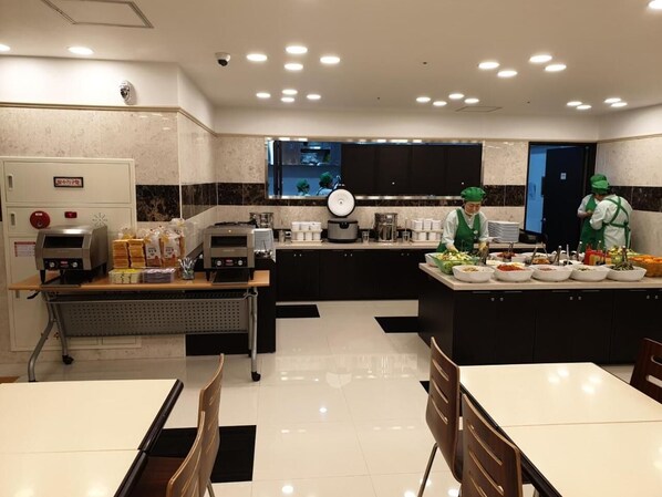 A modern kitchen with a buffet setup, a coffee machine, and a food display area.