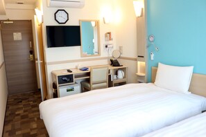 Habitación de hotel con cama, escritorio con computadora, teléfono, reloj y televisor en la pared.