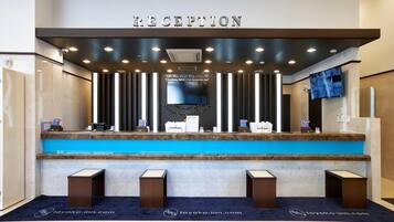 A reception area with a blue counter, a sign above it, and a television on the wall.