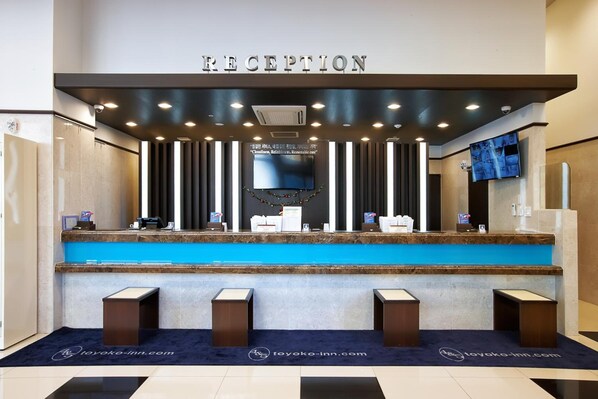 A reception area with a blue counter, a sign above it, and a television on the wall.