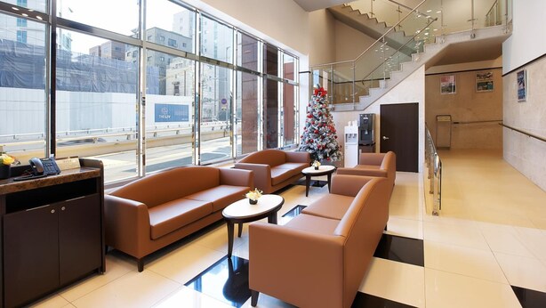 Een ruime lobby met lederen banken, een receptiebalie en een kerstboom.