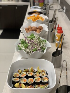 Ein reichhaltiges Buffet mit verschiedenen Speisen, darunter Sushi, Salat, Eier und Beilagen.