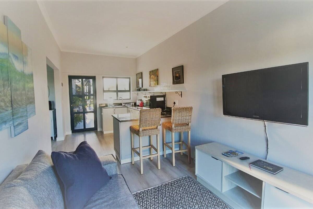 A modern living room with a sofa, a TV, and a kitchen area with bar stools.