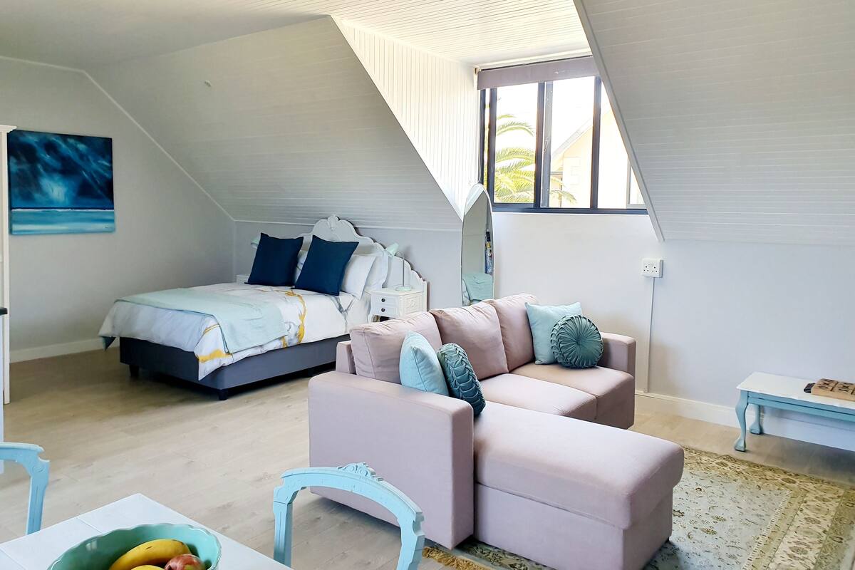 A bedroom with a bed, a sofa, a chair, and a table.
