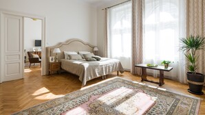 A bedroom with a bed, bedside tables, a nightstand, a potted plant, and a window with curtains. - KrakowRentals - Belle Epoque 1 Apartment (Kraków)