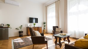 A living room with a sofa, armchair, coffee table, and potted plants. - KrakowRentals - Belle Epoque 1 Apartment (Kraków)