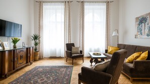 A living room with a brown sofa, armchairs, a coffee table, a TV, and a patterned rug. - KrakowRentals - Belle Epoque 1 Apartment (Kraków)
