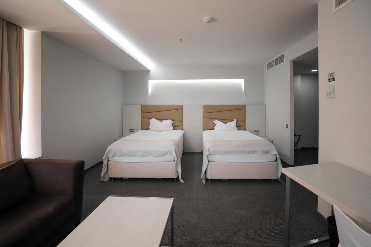 Une chambre d’hôtel avec deux lits, un bureau, un canapé et une grande fenêtre.