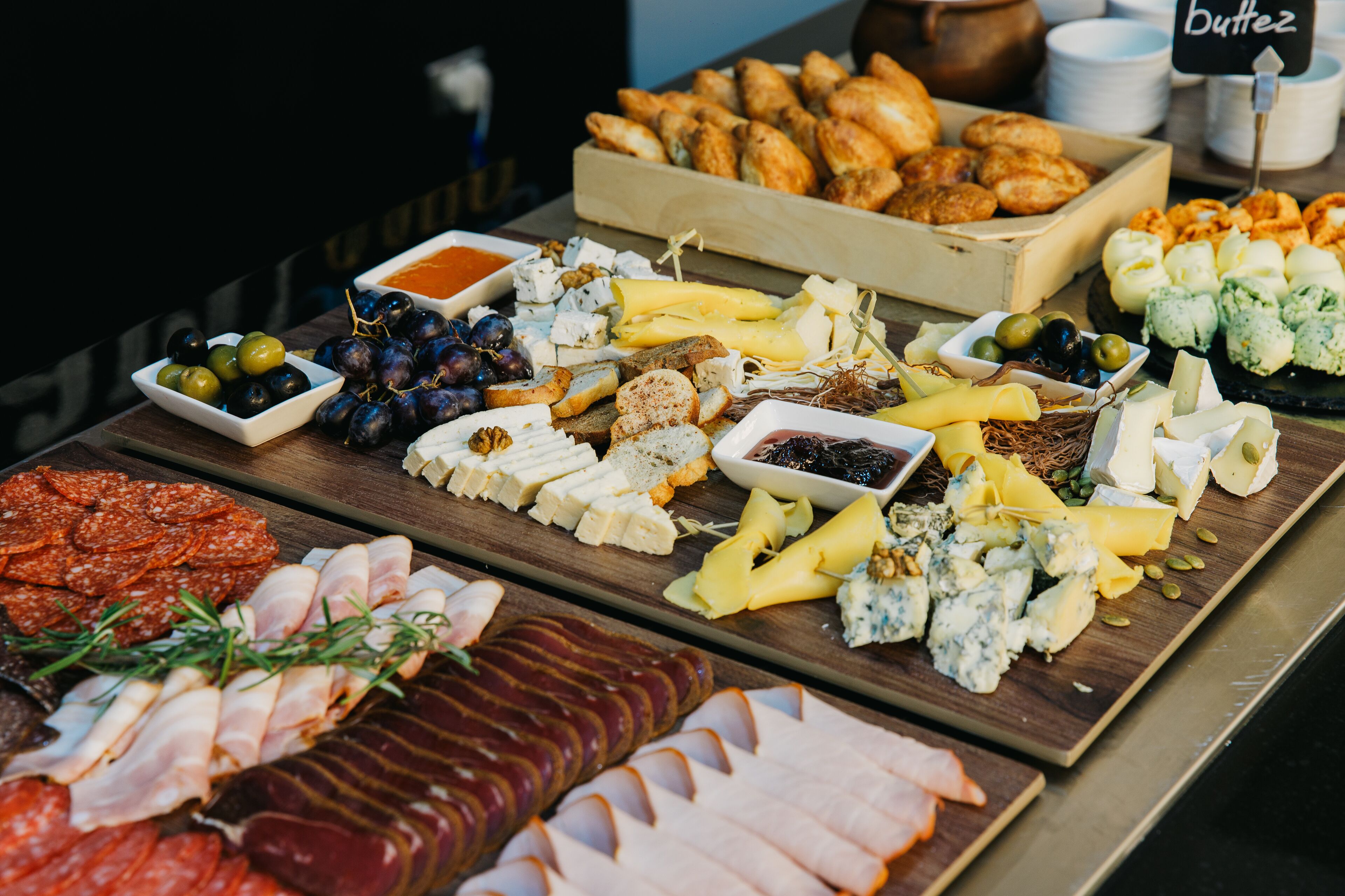 A variety of cheeses, meats, and pastries on a wooden board.