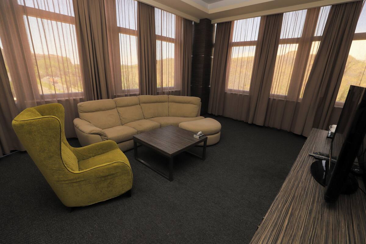 Un salon avec un canapé d’angle beige, un fauteuil jaune, une petite table basse et un téléviseur à écran plat.