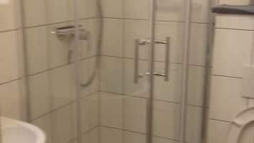A glass-enclosed shower stall with a white sink and toilet to the left.