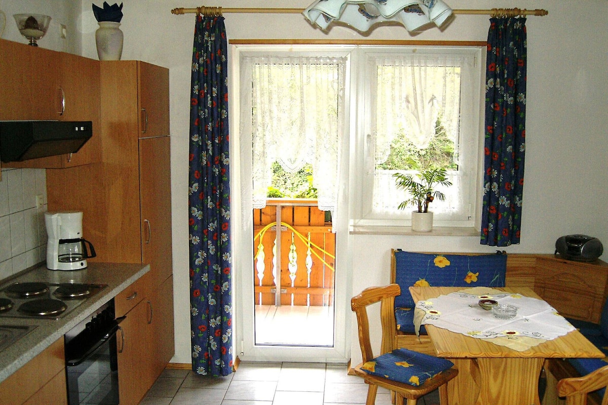 A kitchen with a coffee maker, wooden cabinets, and a dining area with a table and chairs.