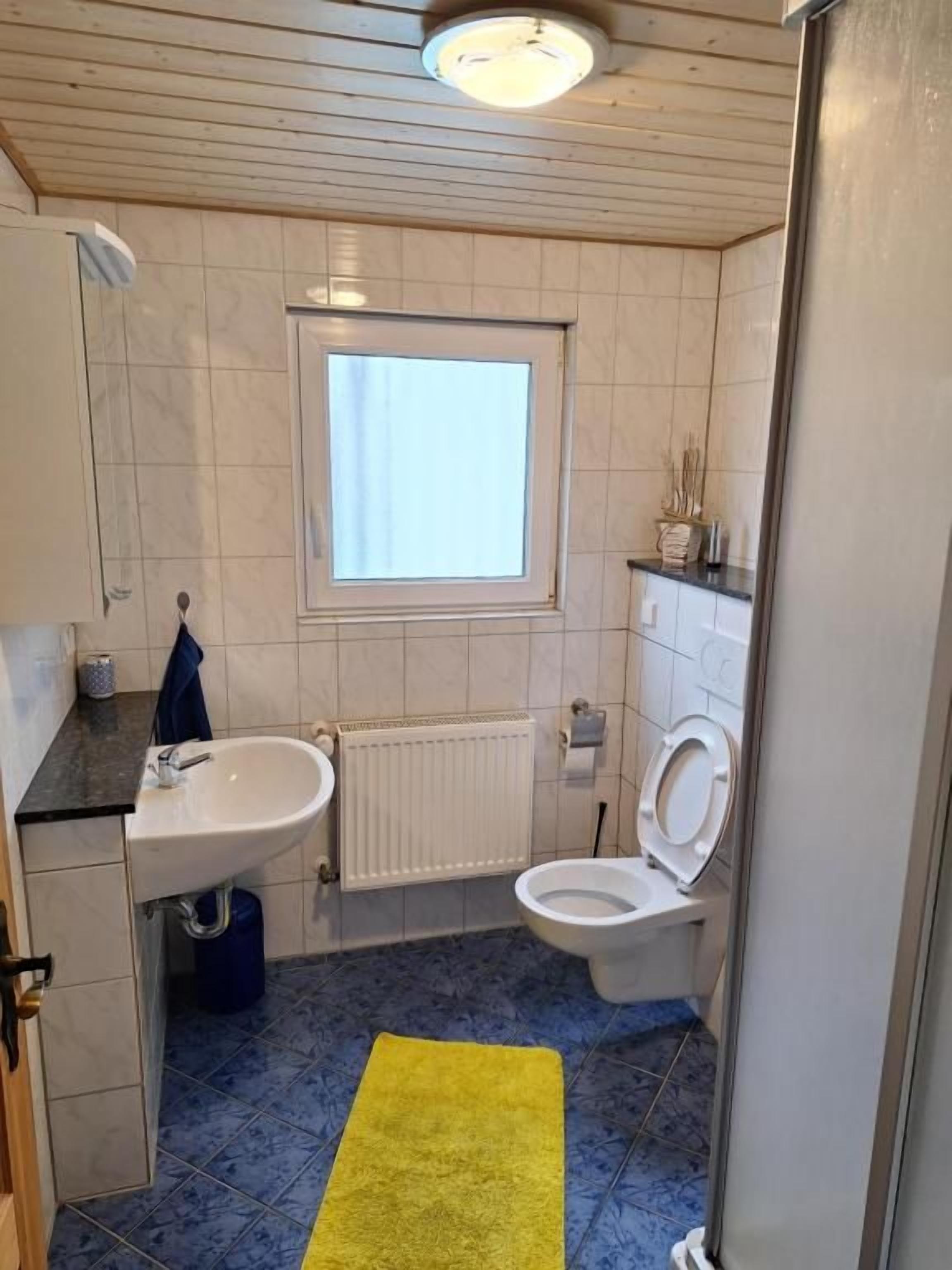 Pieni kylpyhuone, jossa on pesuallas, wc ja ikkuna.