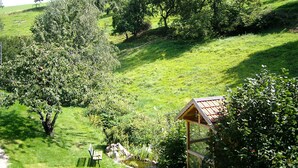 A lush green landscape with a wooden gazebo, a bench, and a small pond. - Gästehaus Rüger (Birkenau)