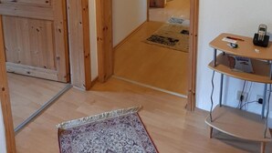 A hallway with wooden doors and a small table with a phone and a magazine. - Gästehaus Rüger (Birkenau)
