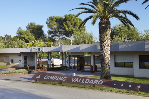 A building with a sign reading "CAMPING VALLDARO" and a palm tree in front. - Càmping Valldaro (Castell-Platja d'Aro)